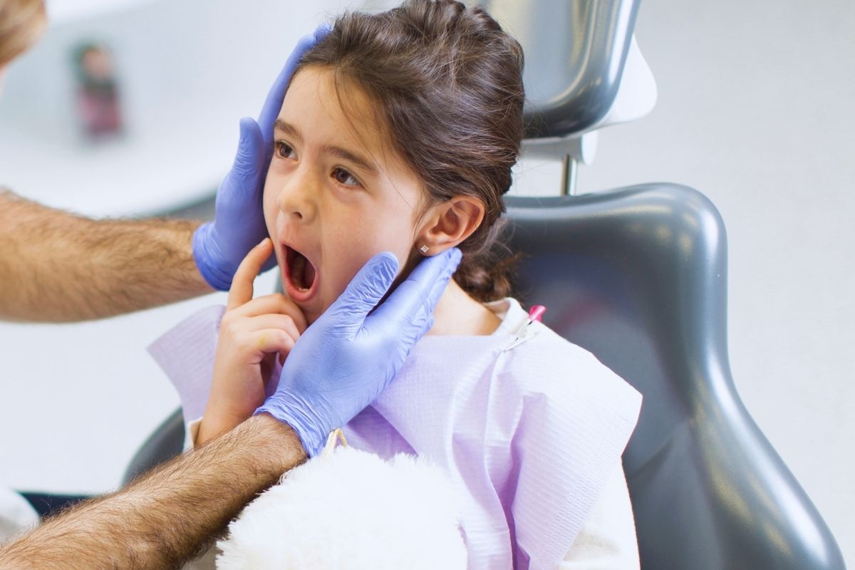 Kid girl showing pain in teeth to the dentist