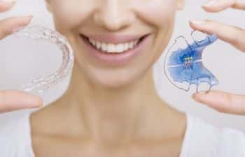 woman holding Invisalign and traditional braces