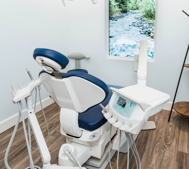 Modern dental operatory chair with blue upholstery in bright, clean clinical treatment room.