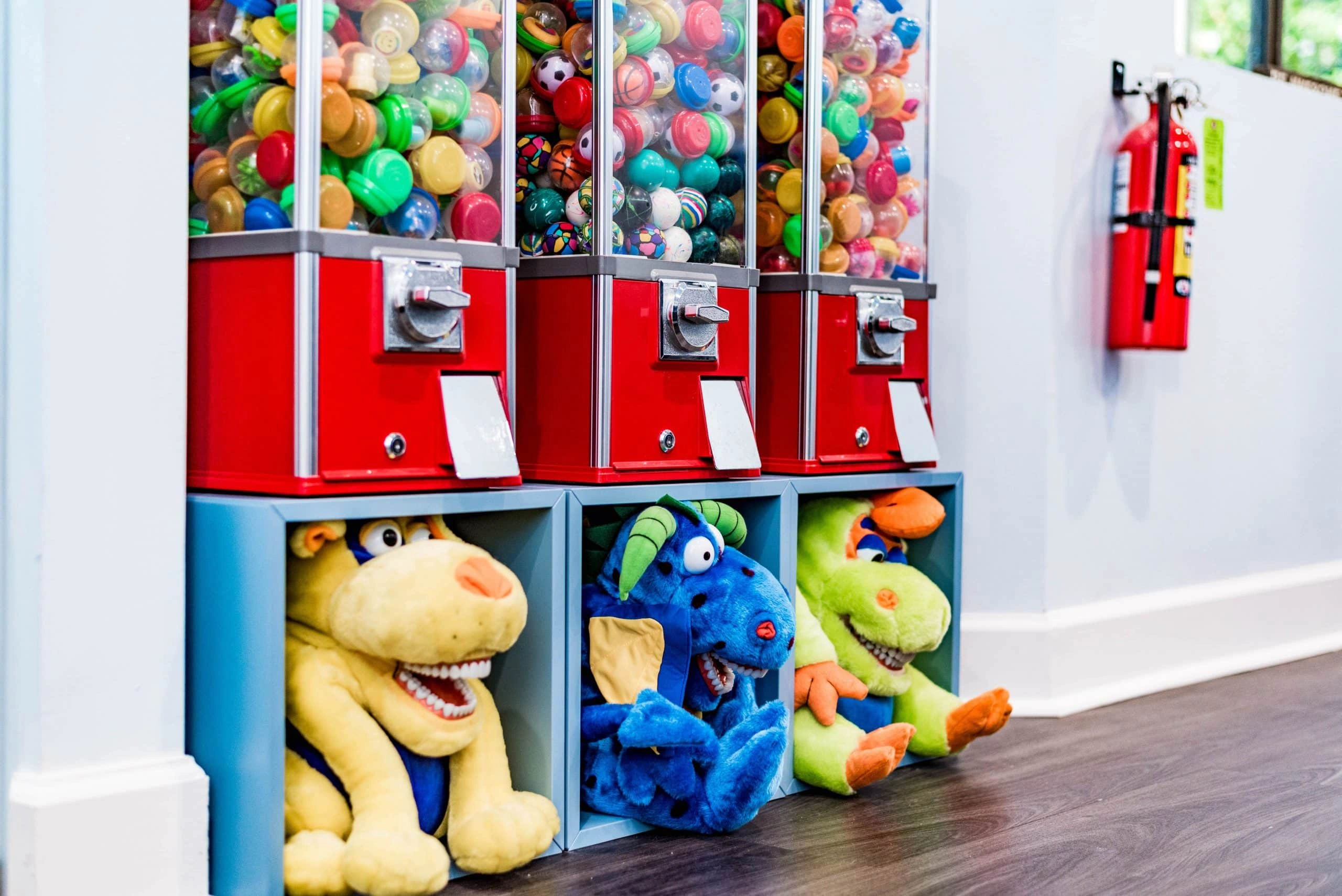 Colorful toy dispensers and stuffed animals in pediatric dental office waiting area.