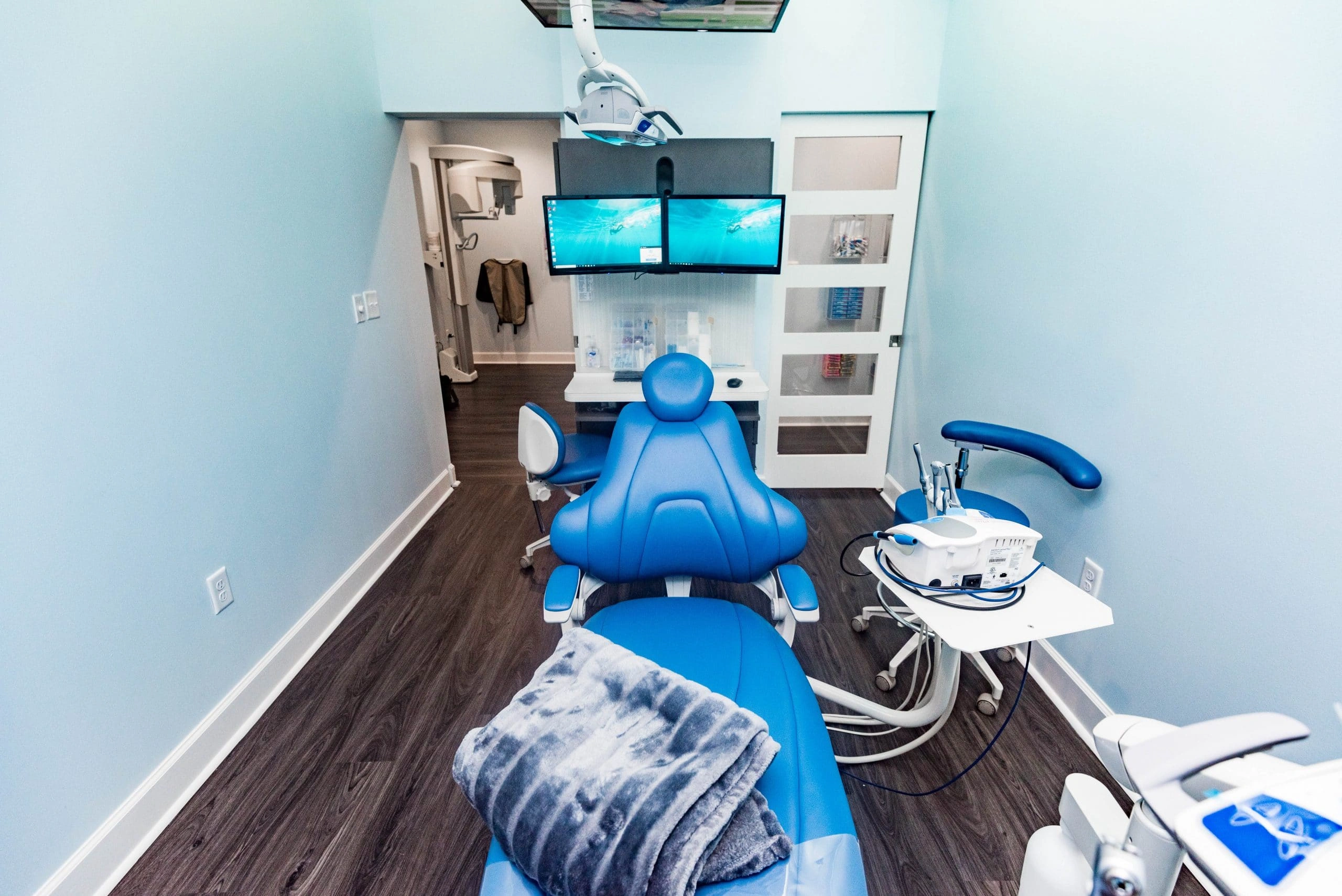 Modern dental treatment room with blue chair, equipment, and organized workspace at Avalon Dental Group clinic.