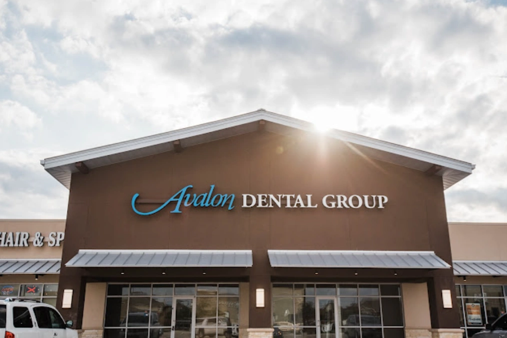 Avalon Dental Group storefront exterior with brown brick facade and blue signage in shopping plaza.