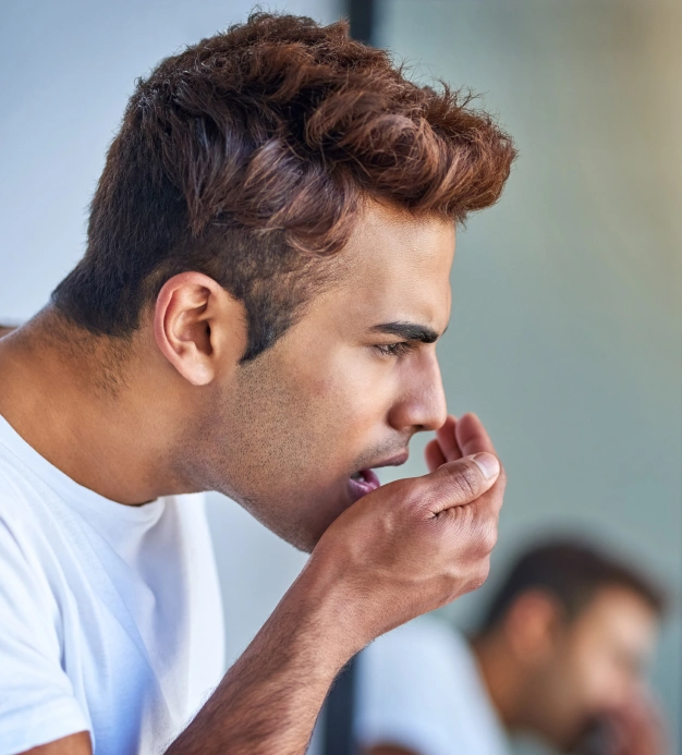 Man in white shirt examining teeth with finger, concerned expression, dental setting.