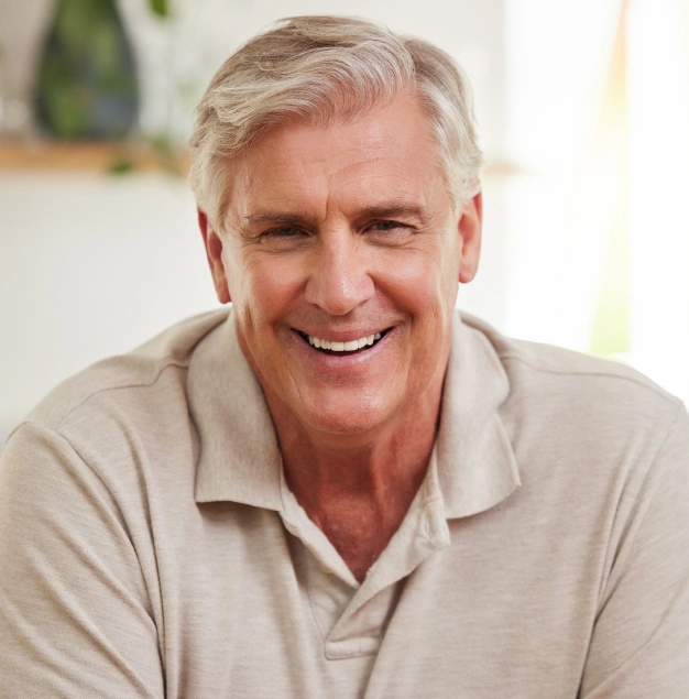 Smiling older man in tan polo shirt, professional headshot for dental practice website.