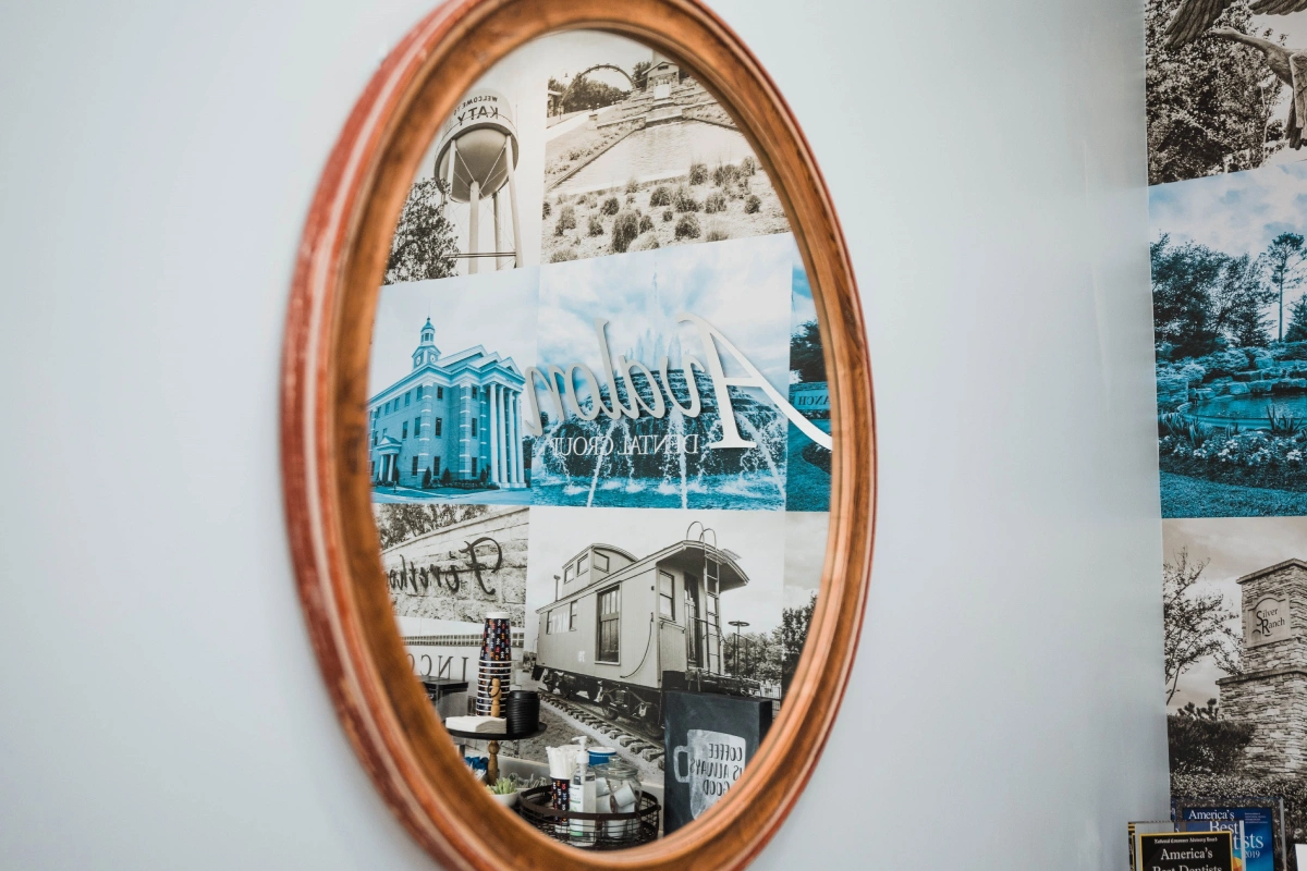 Wooden oval frame displaying three black and white architectural photographs on white wall.