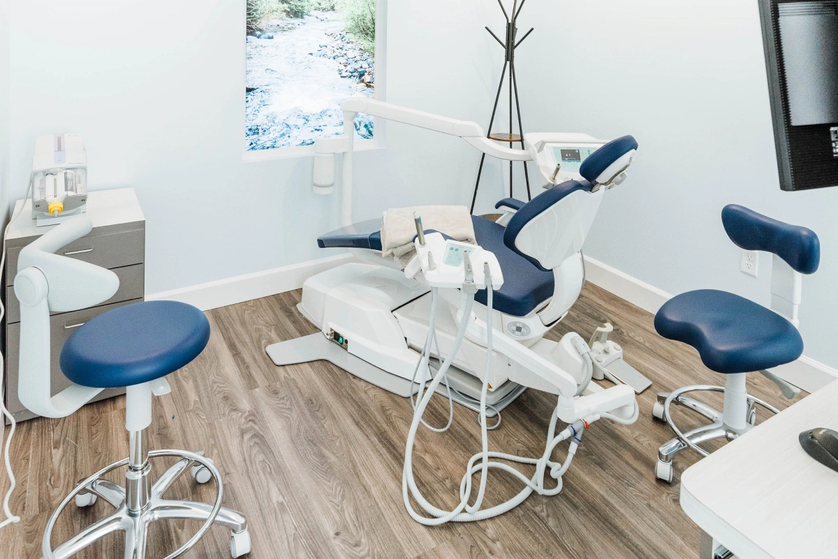 Modern dental operatory with blue upholstered chair, equipment, and wooden flooring at Avalon Dental Group clinic.