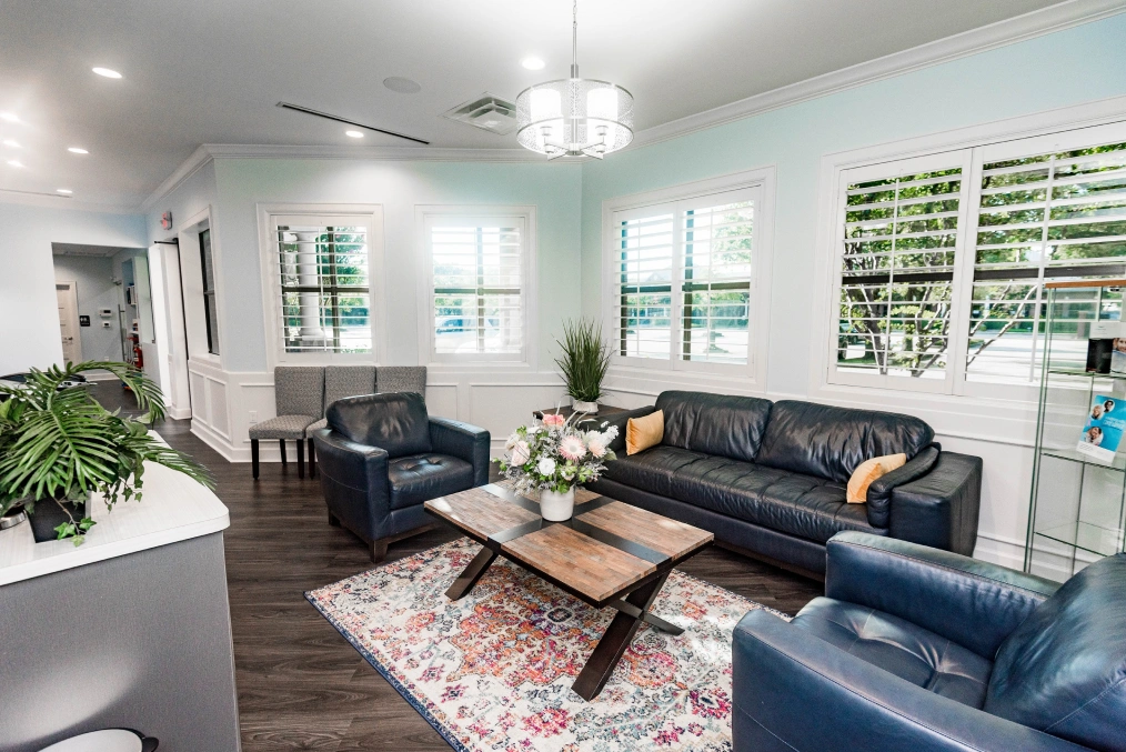 Modern dental office waiting room with navy seating, plants, and natural lighting