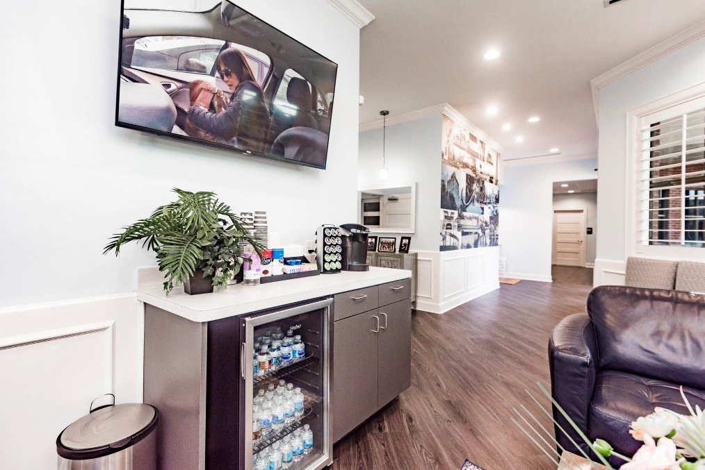 Modern dental office reception area with waiting seating, beverage cooler, and mounted television.