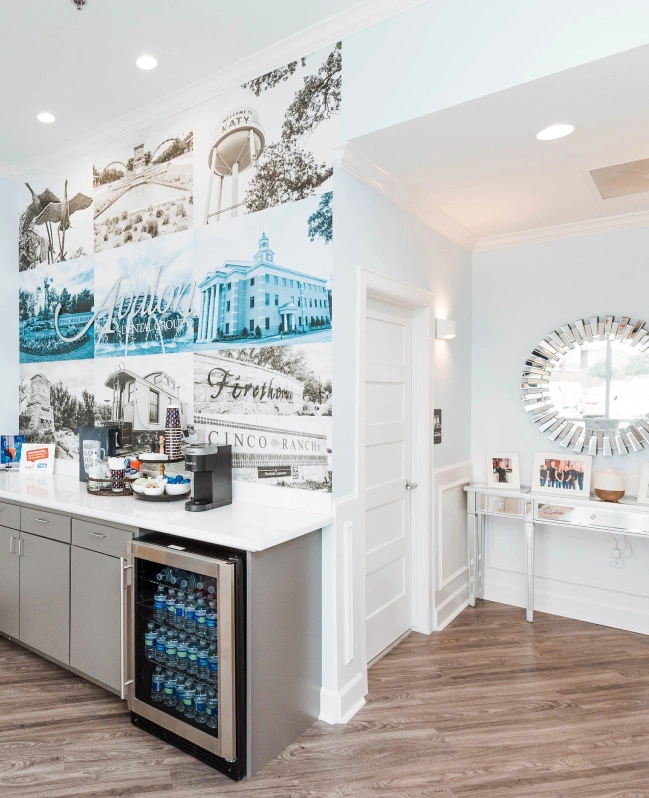 Modern dental office kitchen area with blue-toned photographs on wall and stainless steel appliances.