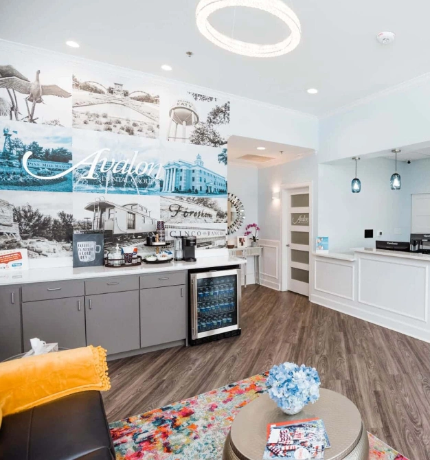 Modern dental office reception area with gray cabinetry, blue accents, and comfortable waiting seating.