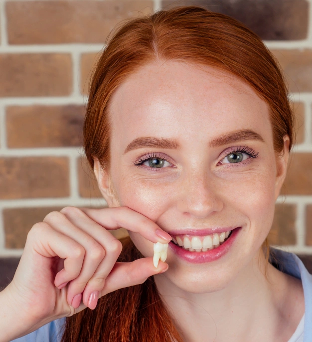 Smiling young woman with red hair holding dental floss against brick wall background.