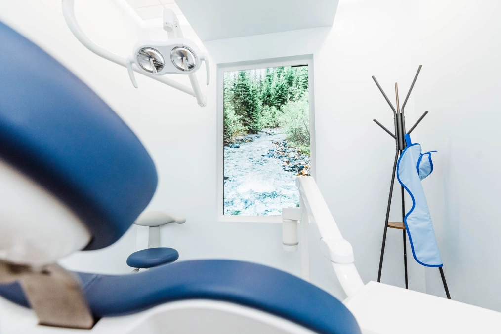 Modern dental office interior with blue chair, window view, and contemporary decor at Avalon Dental Group.