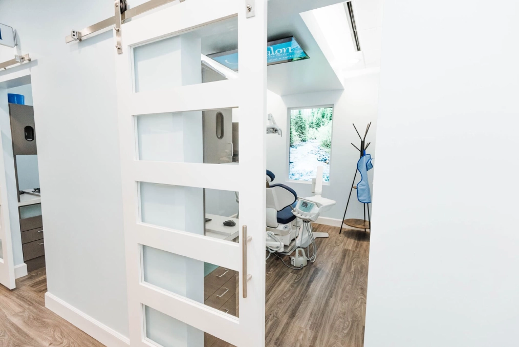 Modern dental office interior with white shelving unit and glass-fronted cabinets displaying supplies and equipment.