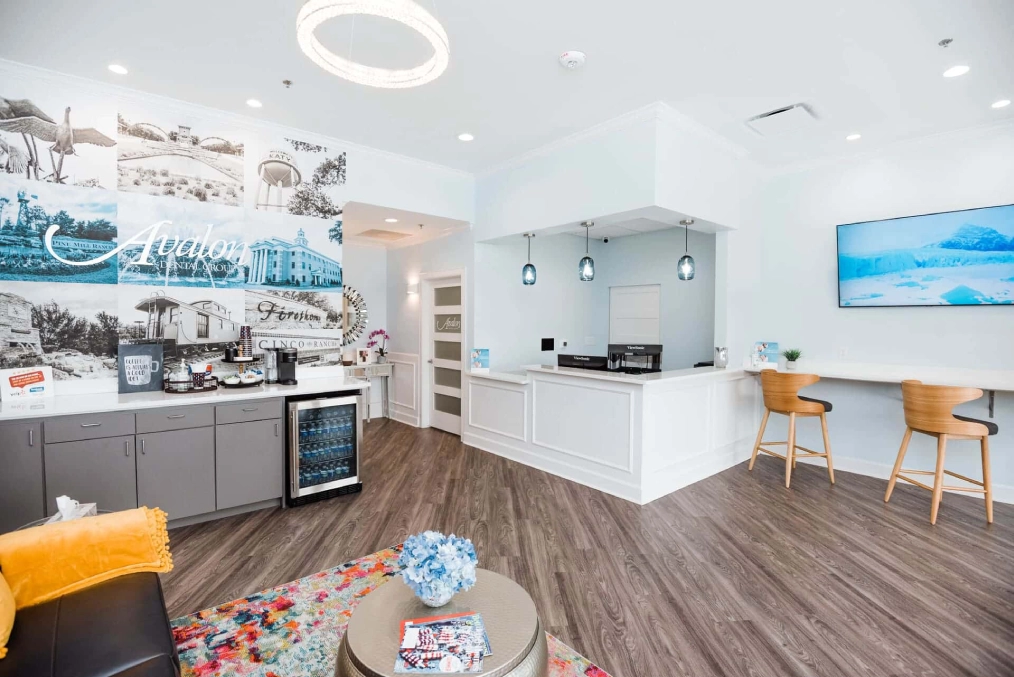 Modern dental office reception area with white counter, waiting seating, and contemporary decor.
