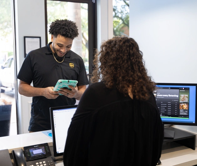 Dental staff member showing patient tablet information at modern dental office reception desk.