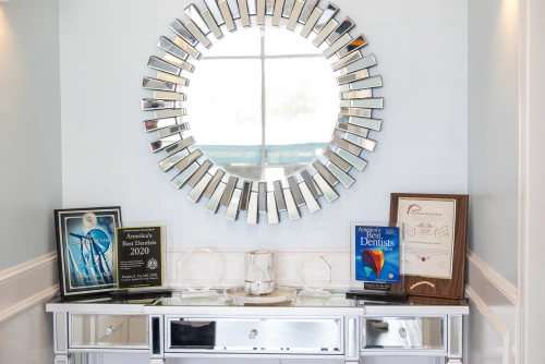 Modern dental office interior with decorative sunburst mirror and white storage console.