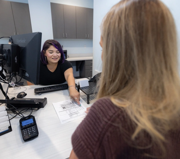 Dental receptionist assists patient at front desk in modern dental office.