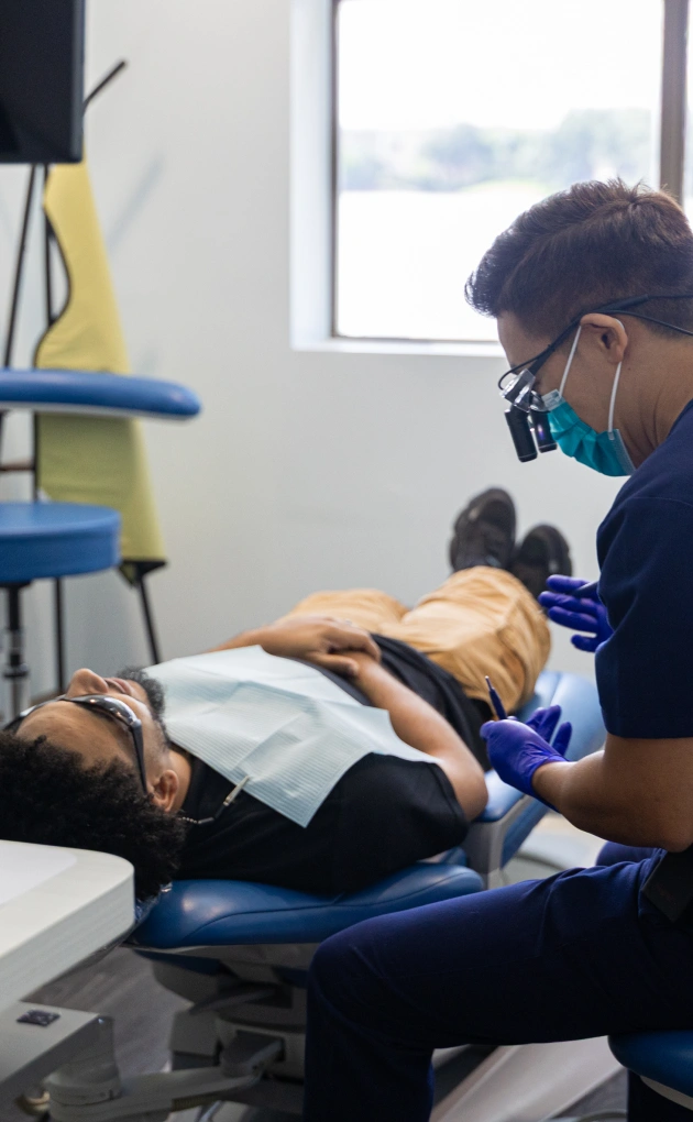 Dentist examining patient's teeth in clinical dental office setting with modern equipment.