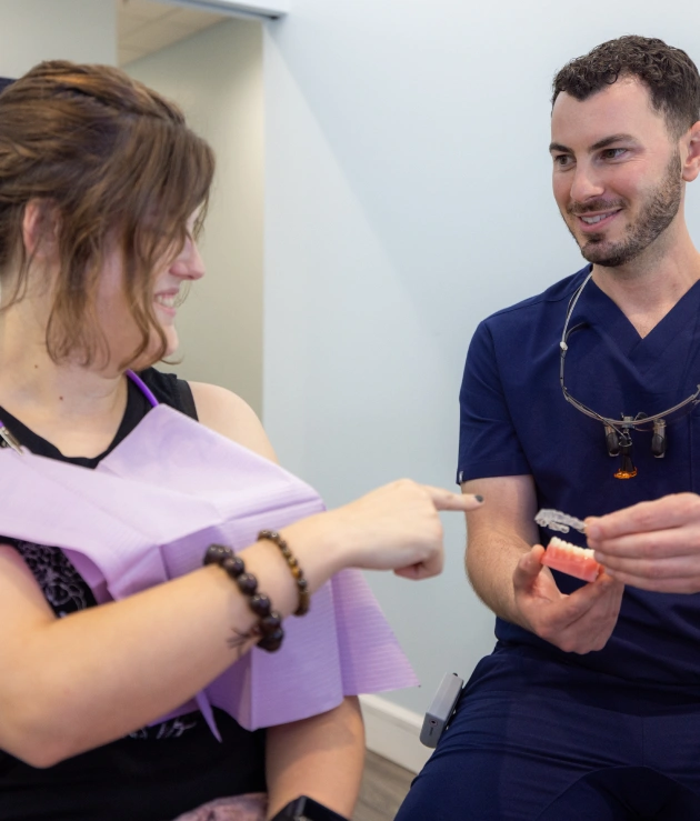 Dental professional examining patient's teeth during consultation in clinical office setting.