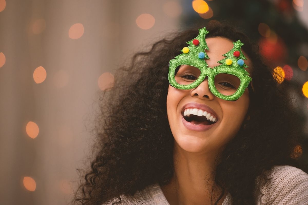 Woman smiling and wearing festive Christmas tree glasses