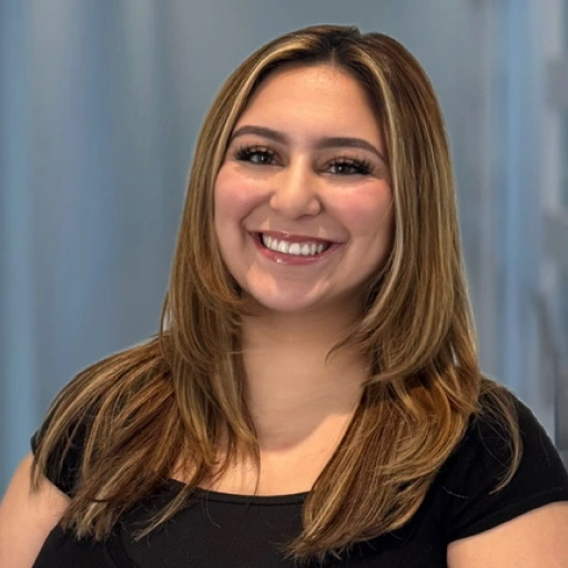 Young woman smiling at camera wearing black shirt against blue striped background.