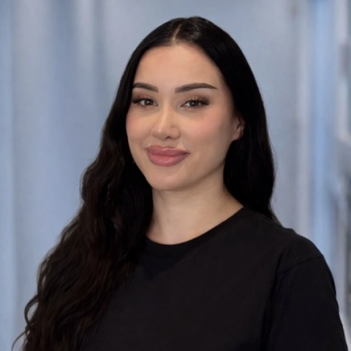 Young woman with long black hair wearing black shirt against light blue background