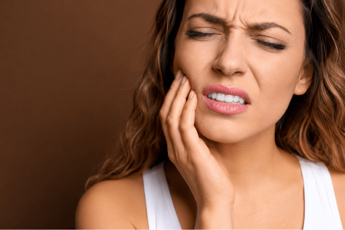Woman experiencing tooth pain that may require restorative dental treatment